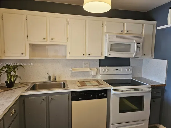 a kitchen with granite countertop white cabinets and white stove