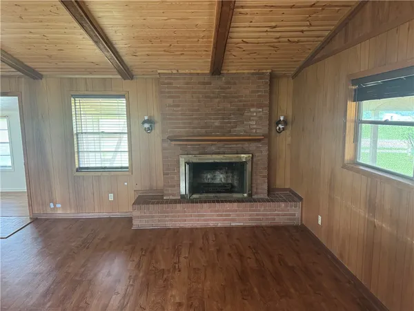 a view of an empty room with wooden floor fireplace and a window