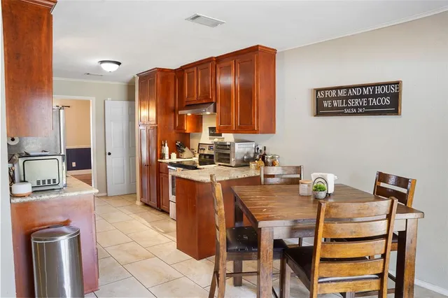 a kitchen with granite countertop a refrigerator a stove a sink a dining table and chairs with wooden floor