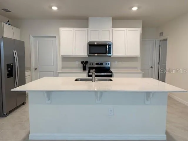 a kitchen with kitchen island a stove a refrigerator and a sink