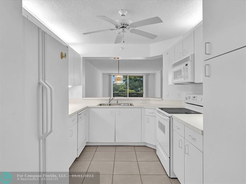 9551 Weldon Circle, Unit E311 Tamarac, FL 33321 - Photo 3 of 64 a kitchen with white cabinets and white appliances