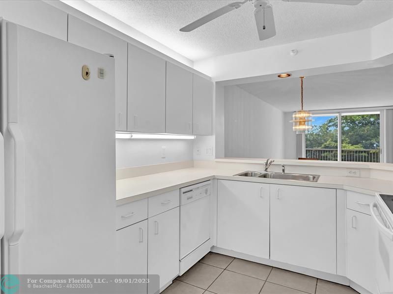 9551 Weldon Circle, Unit E311 Tamarac, FL 33321 - Photo 4 of 64 a kitchen with white cabinets and a sink