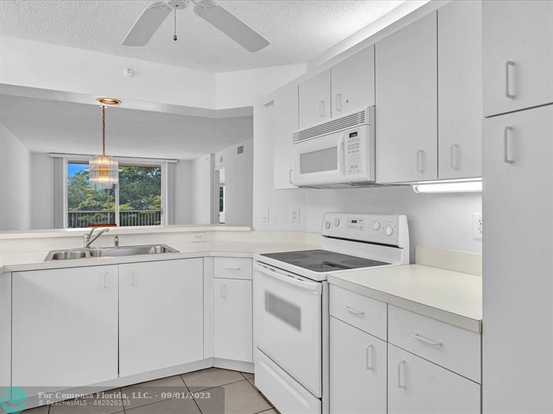 9551 Weldon Circle, Unit E311 Tamarac, FL 33321 - Photo 5 of 64 a kitchen with white cabinets and white appliances