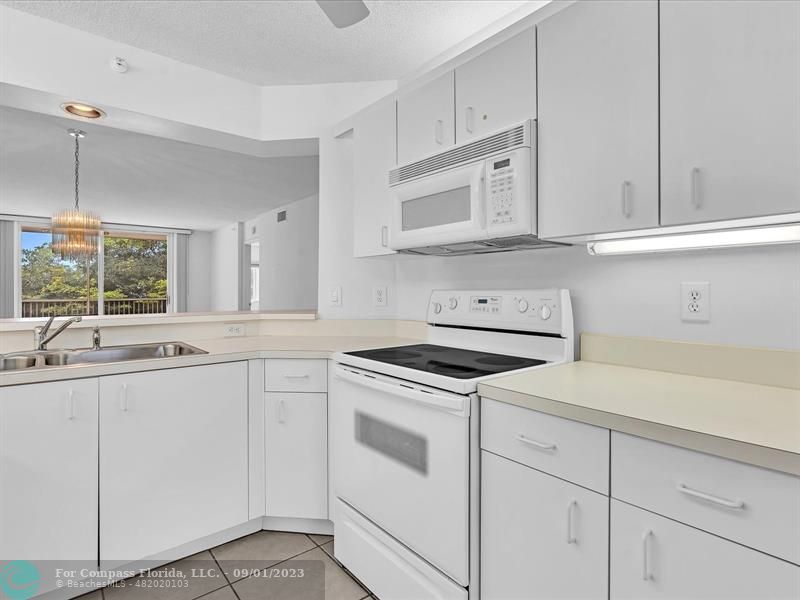 9551 Weldon Circle, Unit E311 Tamarac, FL 33321 - Photo 7 of 64 a kitchen with white cabinets and white appliances