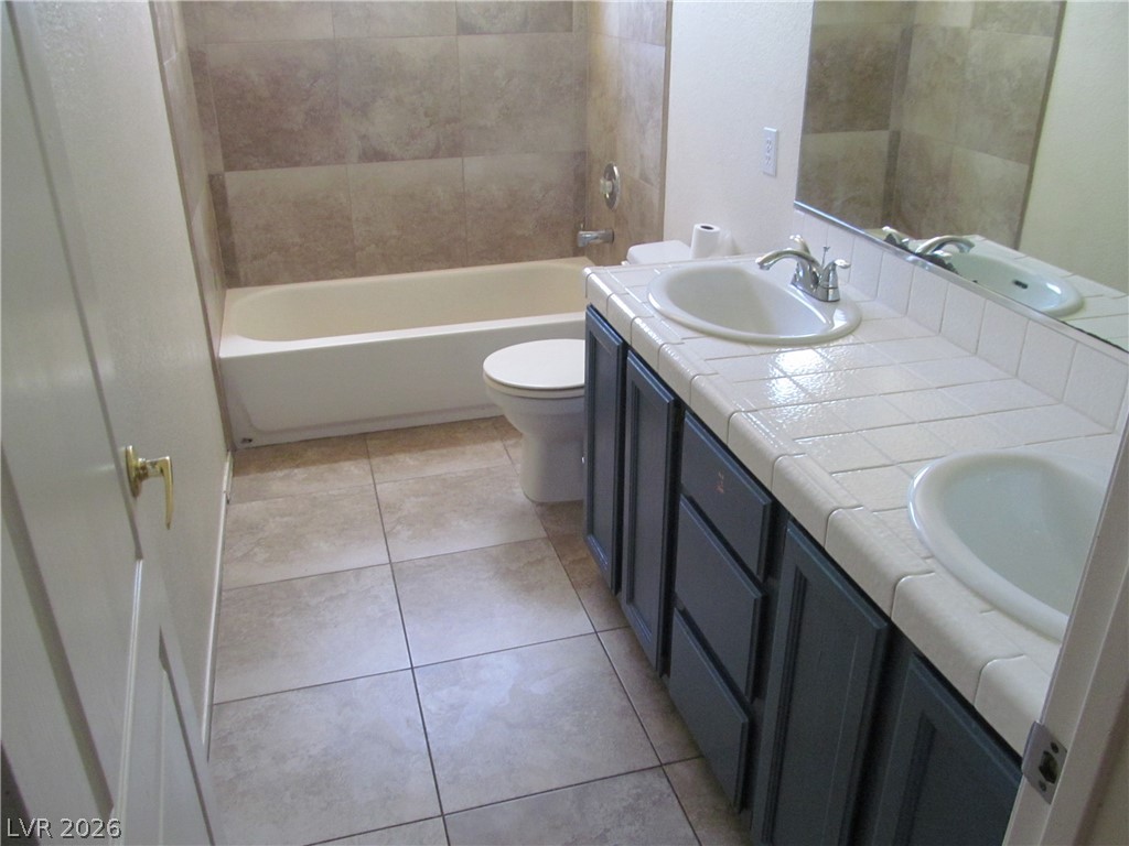 8701 Crescent Ridge Lane Las Vegas, NV 89134 - Photo 18 of 28 A well-appointed bathroom features a practical vanity with double sinks, set against a backdrop of durable tile flooring.