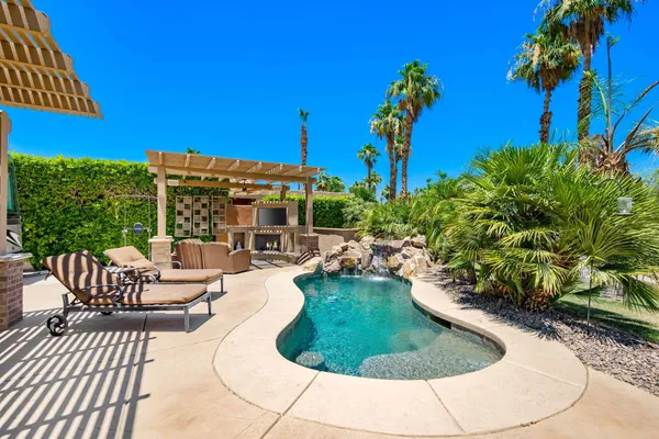 a view of a house with backyard sitting area and swimming pool