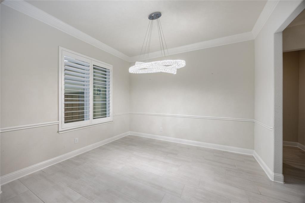 918 Sydney Lane Allen, TX 75013 - Photo 12 of 40 This room features light-colored walls with decorative trim, light wood-look flooring, and a modern ceiling light fixture