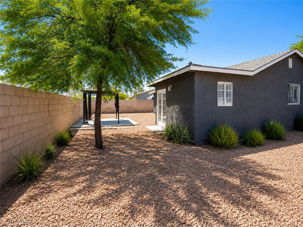 2870 South Sandhill Road Las Vegas, NV 89121 - Photo 18 of 64 A well-maintained side yard features a sturdy block wall, gravel landscaping, and mature foliage providing pleasant shade.