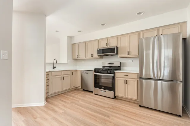 a kitchen with a refrigerator stove and wooden cabinets