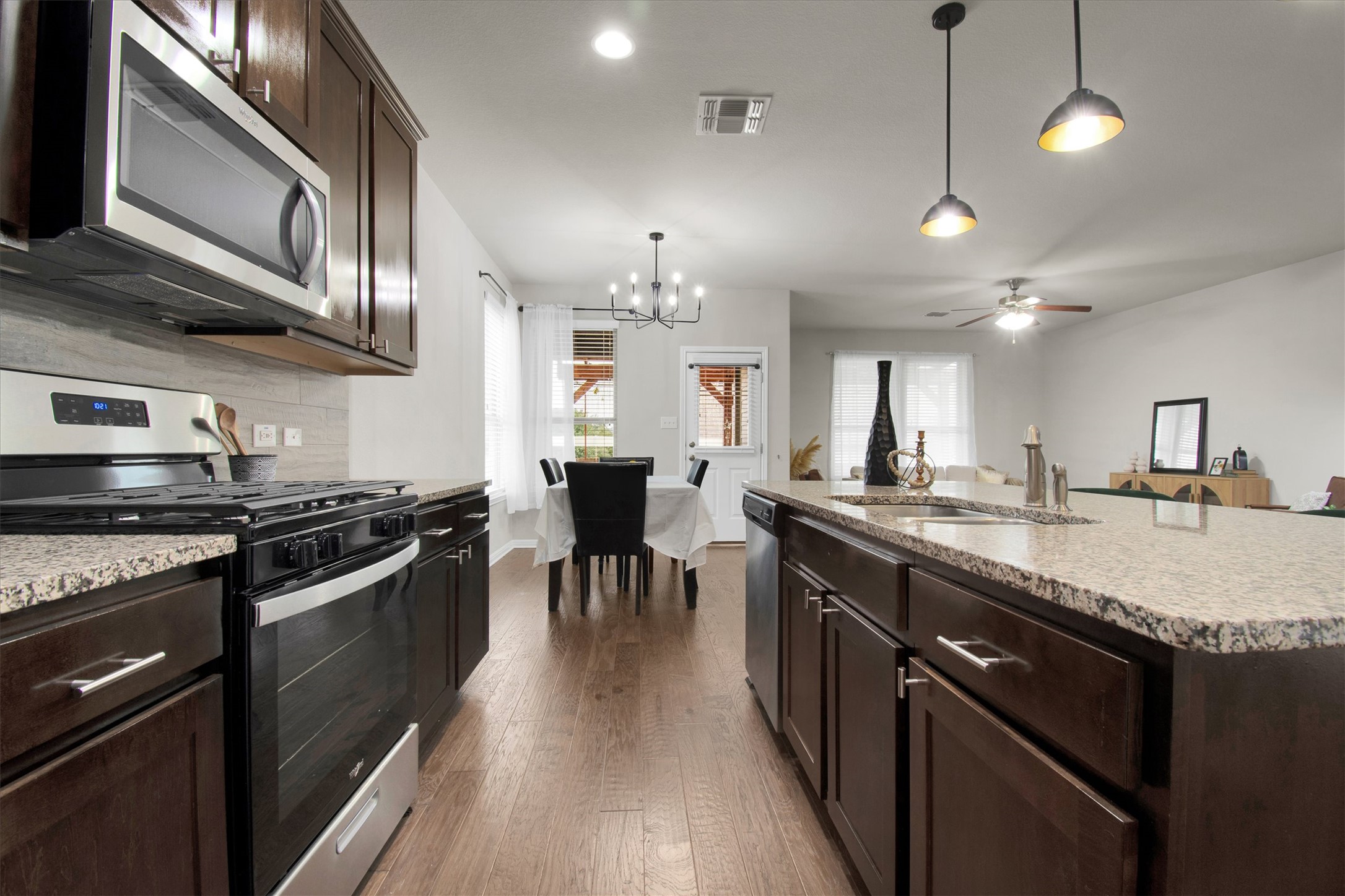 13601 Larrys Lane Manchaca, TX 78652 - Photo 5 of 40 Kitchen featuring dark brown cabinetry, stainless steel appliances, pendant lighting, light stone countertops, and recessed lighting