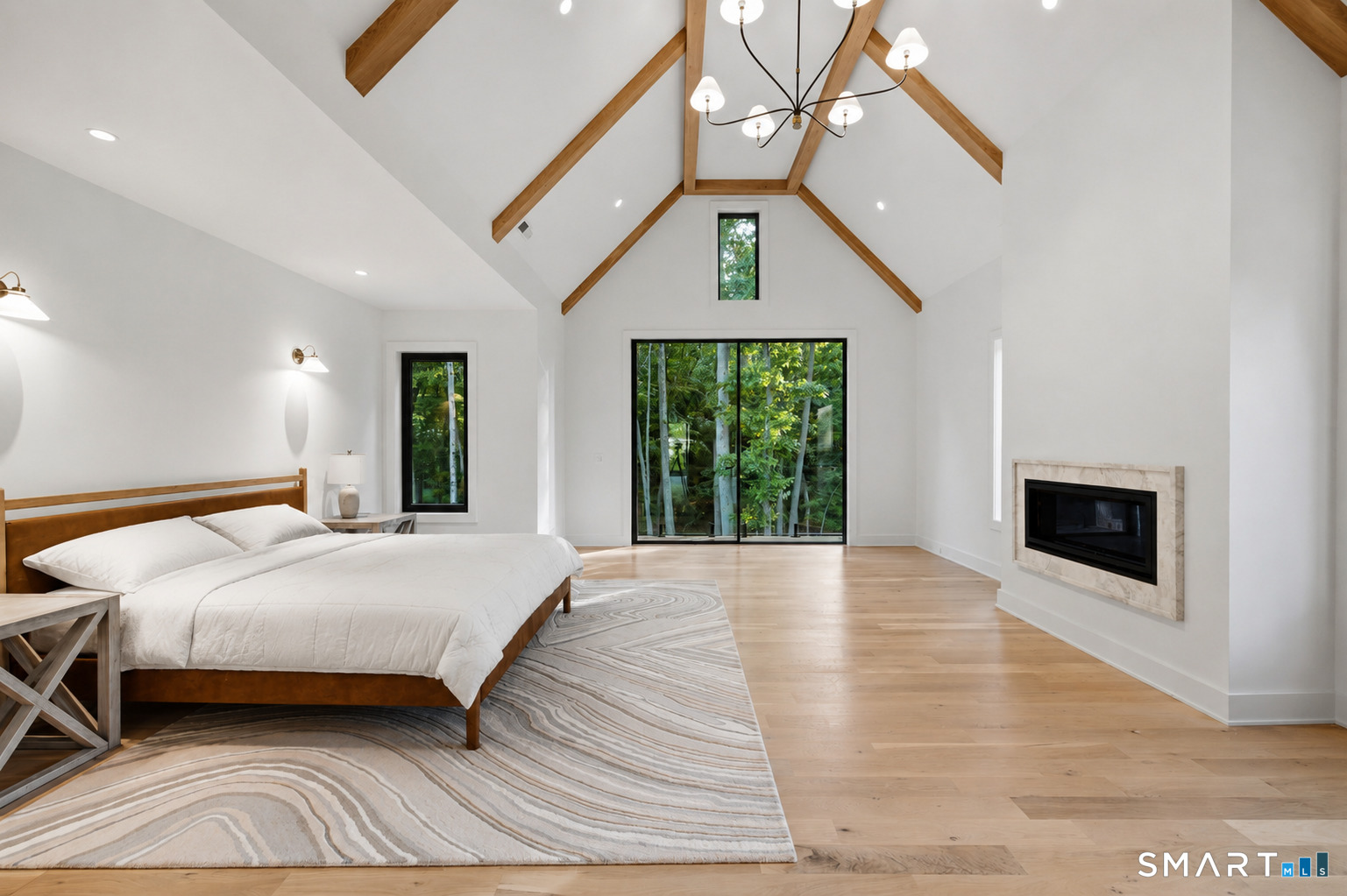 2 Windy Hill Road Westport, CT 06880 - Photo 17 of 40 a spacious bedroom with a large bed a chandelier and fireplace