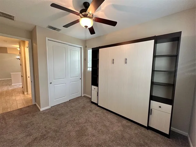 an empty room with closet and a ceiling fan