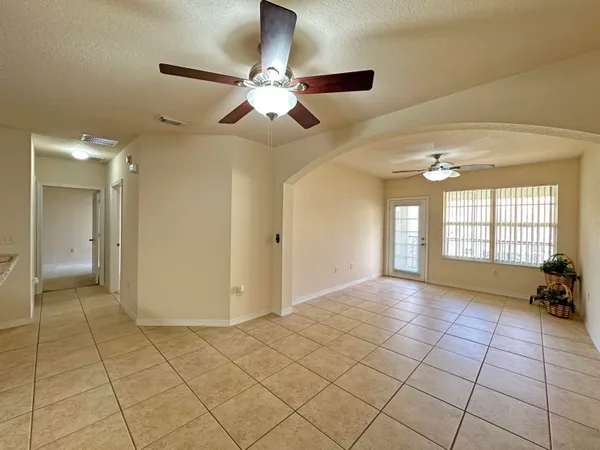 a view of an empty room and window and a chandelier fan