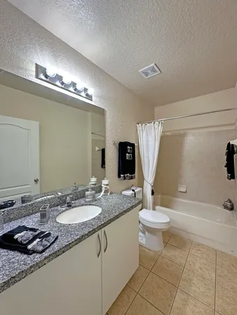 a bathroom with a granite countertop sink a toilet and shower
