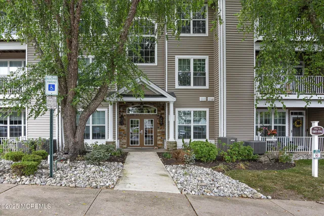 a view of a brick house with large windows and plants
