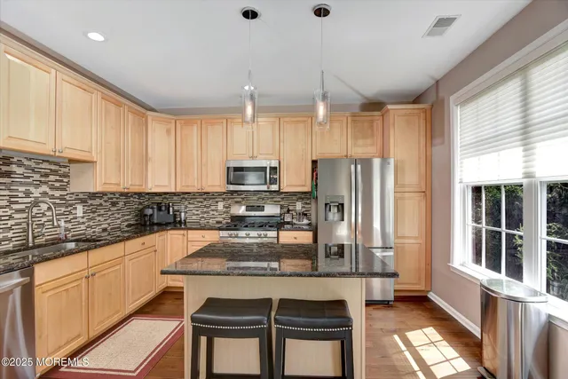 a kitchen with stainless steel appliances granite countertop a stove a sink and a refrigerator