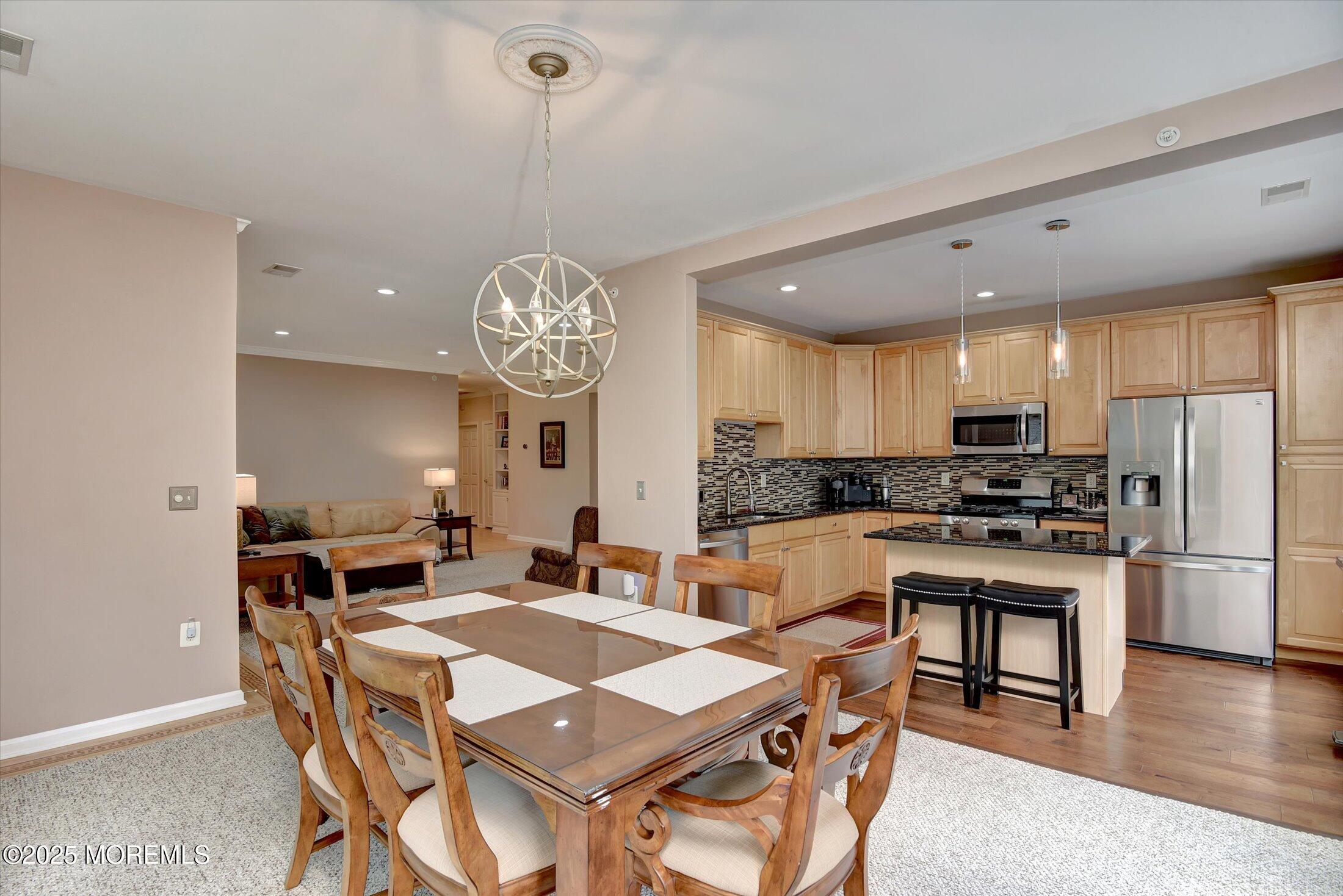 594 St Andrews Place Manalapan, NJ 07726 - Photo 6 of 35 a view of a dining room and livingroom with furniture wooden floor a rug a painting and a chandelier