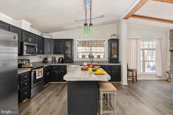 a kitchen with stainless steel appliances wooden floors and a view of living room