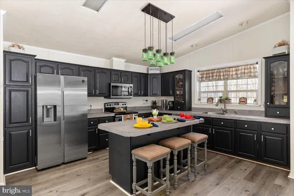 a kitchen with stainless steel appliances a table chairs refrigerator and microwave