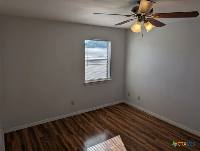 a view of an empty room with window and chandelier fan