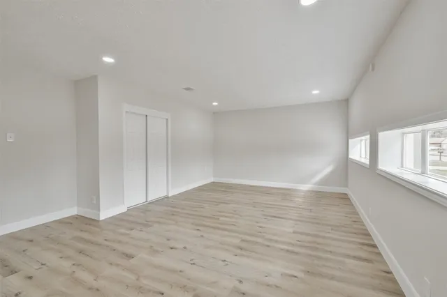 a view of empty room with wooden floor and fan