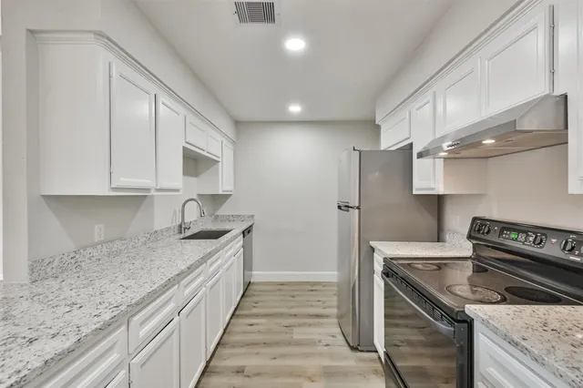 a kitchen with stainless steel appliances granite countertop a sink stove and refrigerator