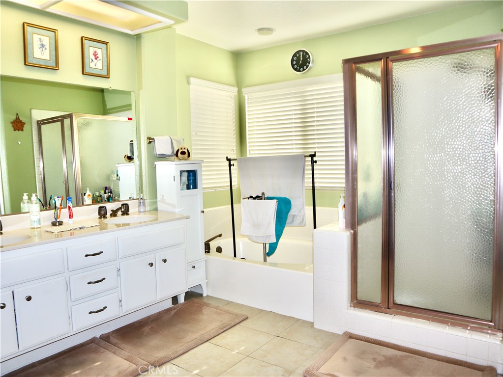 21475 Dickinson Road Moreno Valley, CA 92557 - Photo 20 of 41 a spacious bathroom with a double vanity sink a mirror a bathtub and next to a window