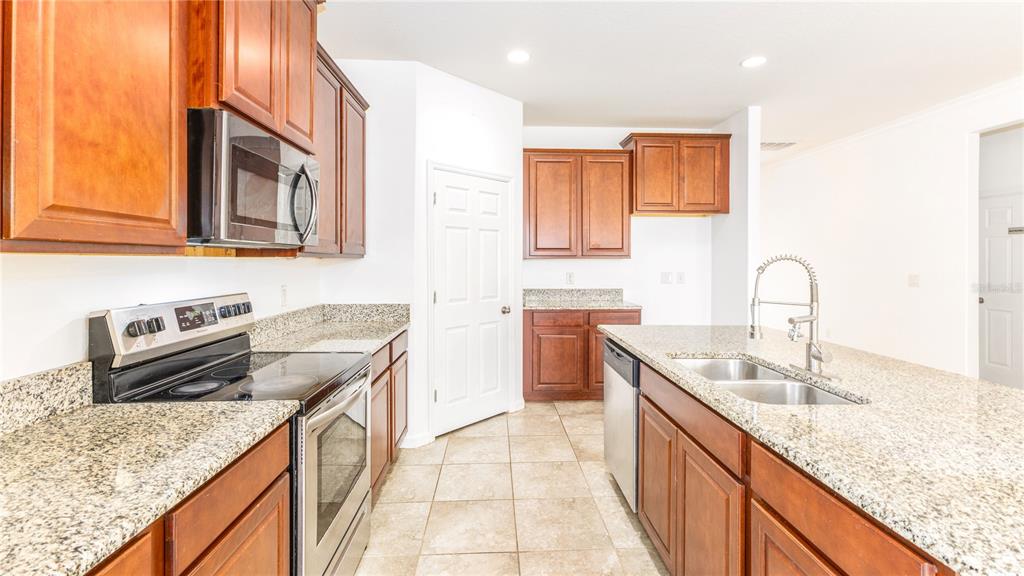 1723 Musgrass Circle Melbourne, FL 32904 - Photo 9 of 31 a kitchen with granite countertop stainless steel appliances sink stove microwave and cabinets