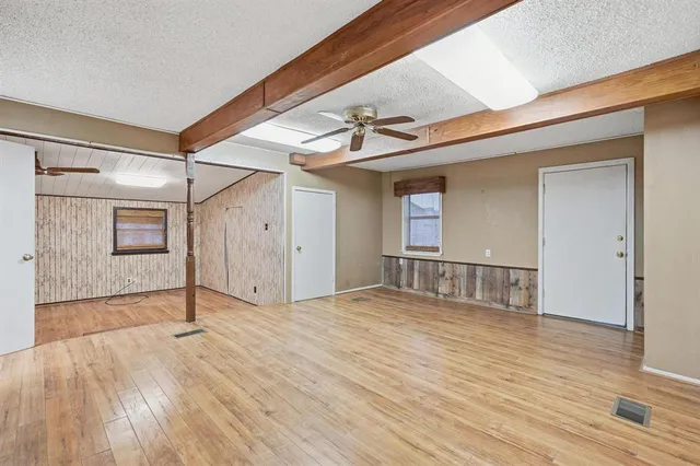 a view of empty room with wooden floor and fan