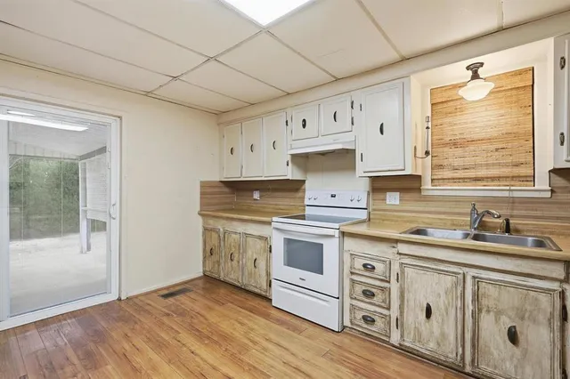 a kitchen with granite countertop a sink cabinets stainless steel appliances and a window