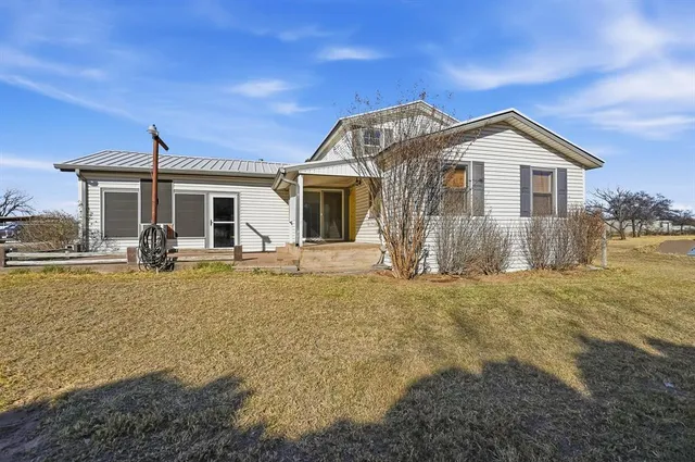 a front view of house with yard and trees in the background