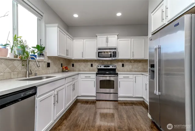 a kitchen with a sink stainless steel appliances and white cabinets
