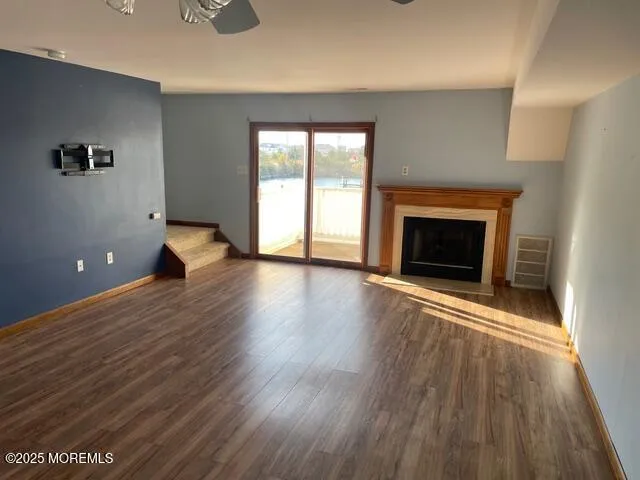a view of an empty room with window and wooden floor