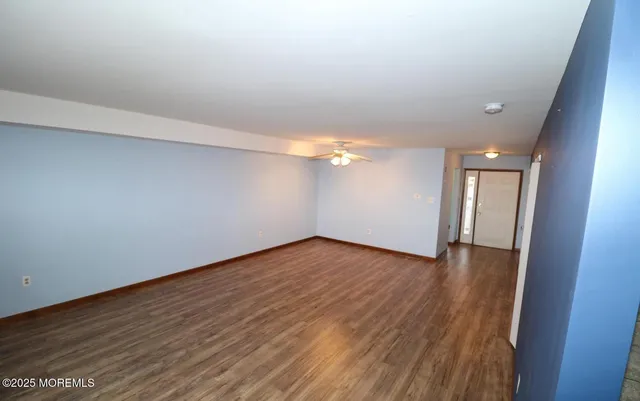 a view of an empty room with wooden floor fireplace and a window