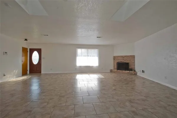 an empty room with windows and fireplace