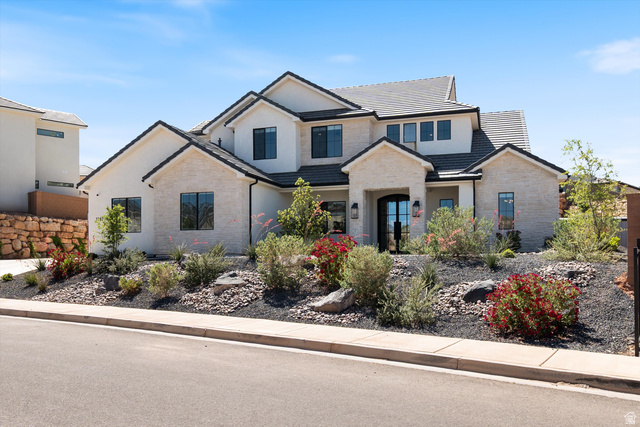 Contemporary exterior featuring white stucco, light-colored stone veneer accents, and a dark-tiled roof