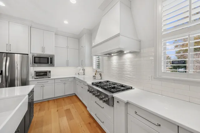 a kitchen with stainless steel appliances a refrigerator a stove and white cabinets