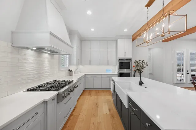 a large kitchen with stainless steel appliances a sink a stove and cabinets