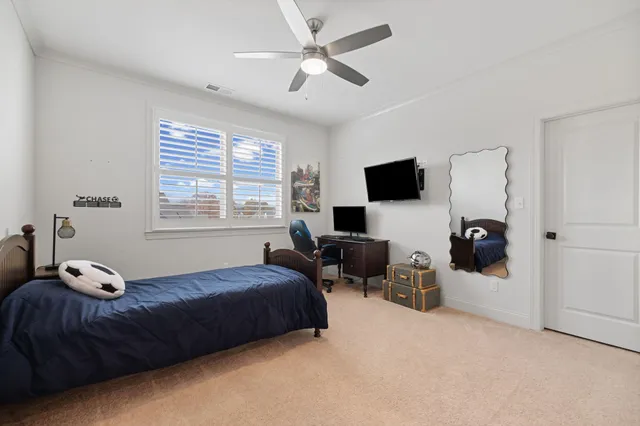 a bedroom with a bed couches and a flat tv screen