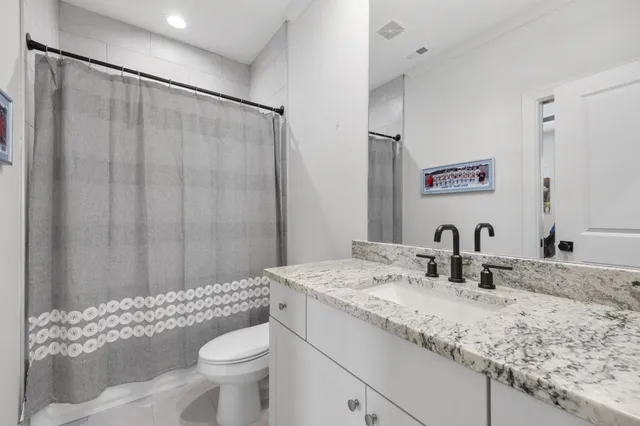 a bathroom with a granite countertop sink toilet and a mirror