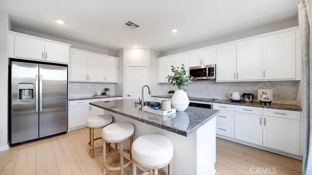 a kitchen with stainless steel appliances granite countertop a sink a stove a refrigerator cabinets and dining table