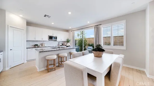 a kitchen with stainless steel appliances kitchen island granite countertop a stove a sink a refrigerator and white cabinets with wooden floor