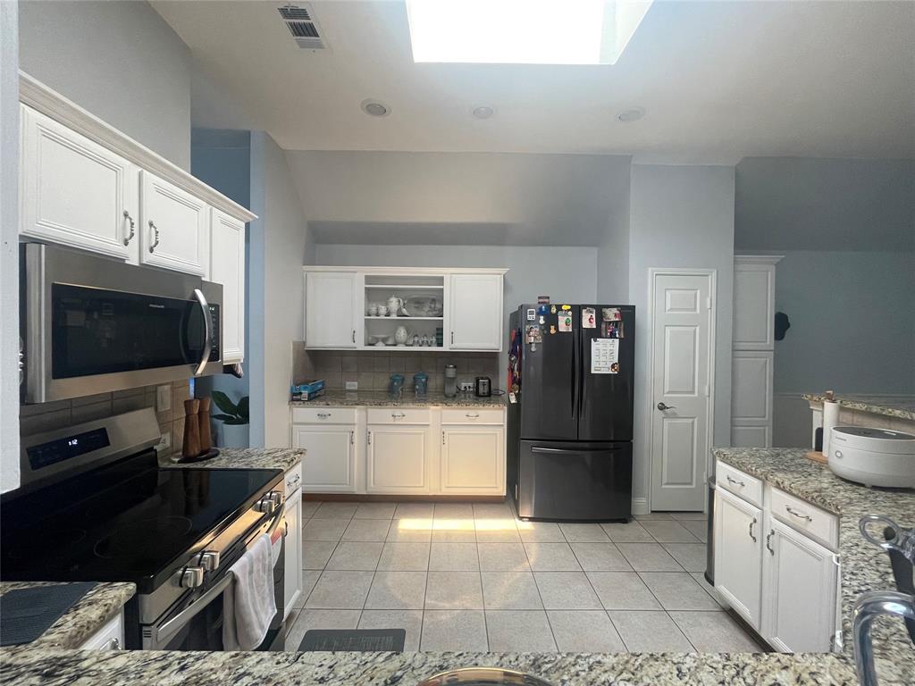7916 Country Ridge Lane Plano, TX 75024 - Photo 12 of 27 a kitchen with a refrigerator and a stove top oven