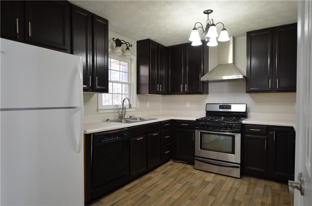 140 Stewart Drive Dallas, GA 30132 - Photo 6 of 21 a kitchen with stainless steel appliances granite countertop a stove a refrigerator and a sink with wooden cabinets