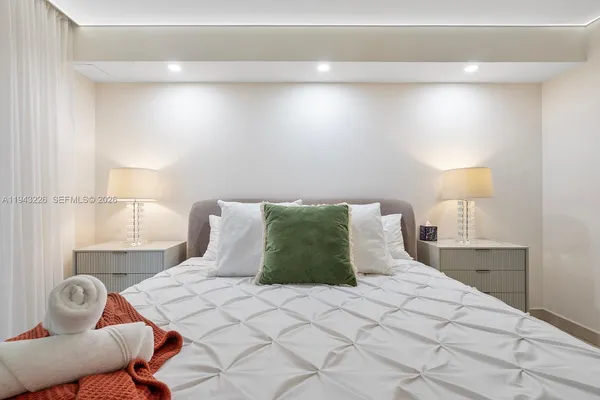a bedroom with a bed and a lamp on dresser