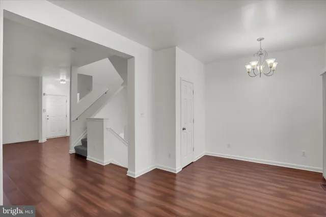 a view of an empty room with wooden floor and stairs