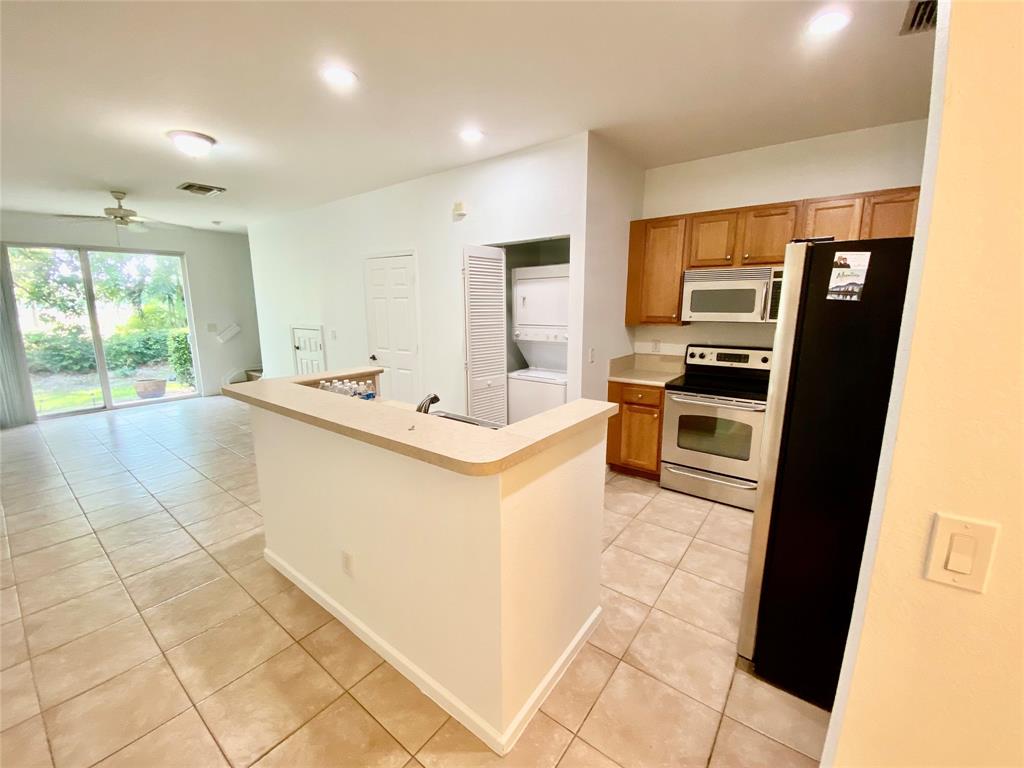 8720 Cypress Walk Court, Unit 8720 Tamarac, FL 33321 - Photo 16 of 36 a kitchen with stainless steel appliances a stove a sink and a refrigerator
