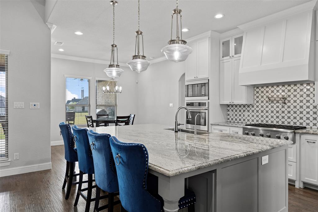 6381 Rigel Road Godley, TX 76044 - Photo 18 of 40 a kitchen with granite countertop a table chairs and wooden floor