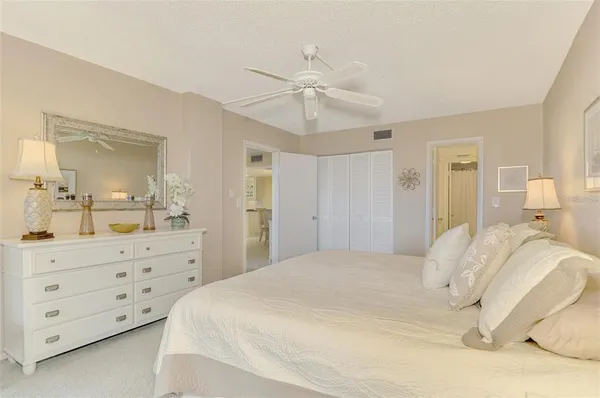 a bedroom with a bed a chandelier and a mirror on dresser
