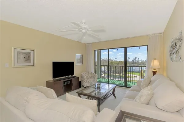 a living room with furniture a flat screen tv and a floor to ceiling window